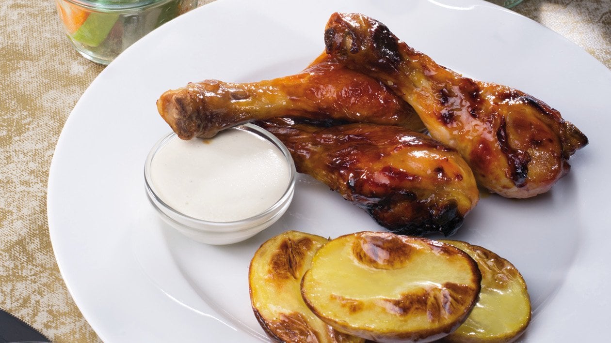 Medové kuřecí paličky s pečeným bramborem, zeleninou a sýrovým dipem.