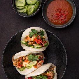 Nadýchaný bun plněný trhaným kuřecím masem s hoisin a chilli omáčkou, nakládanou okurkou, koriandrem a chilli